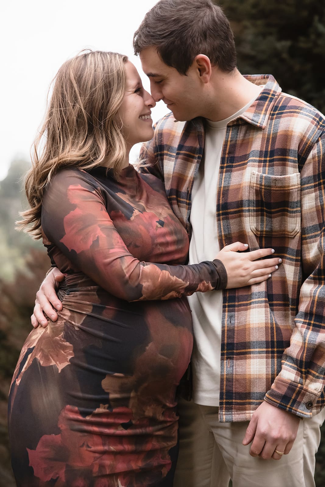Couple embracing in rust and neutral outfits during an outdoor maternity photography session in Melbourne