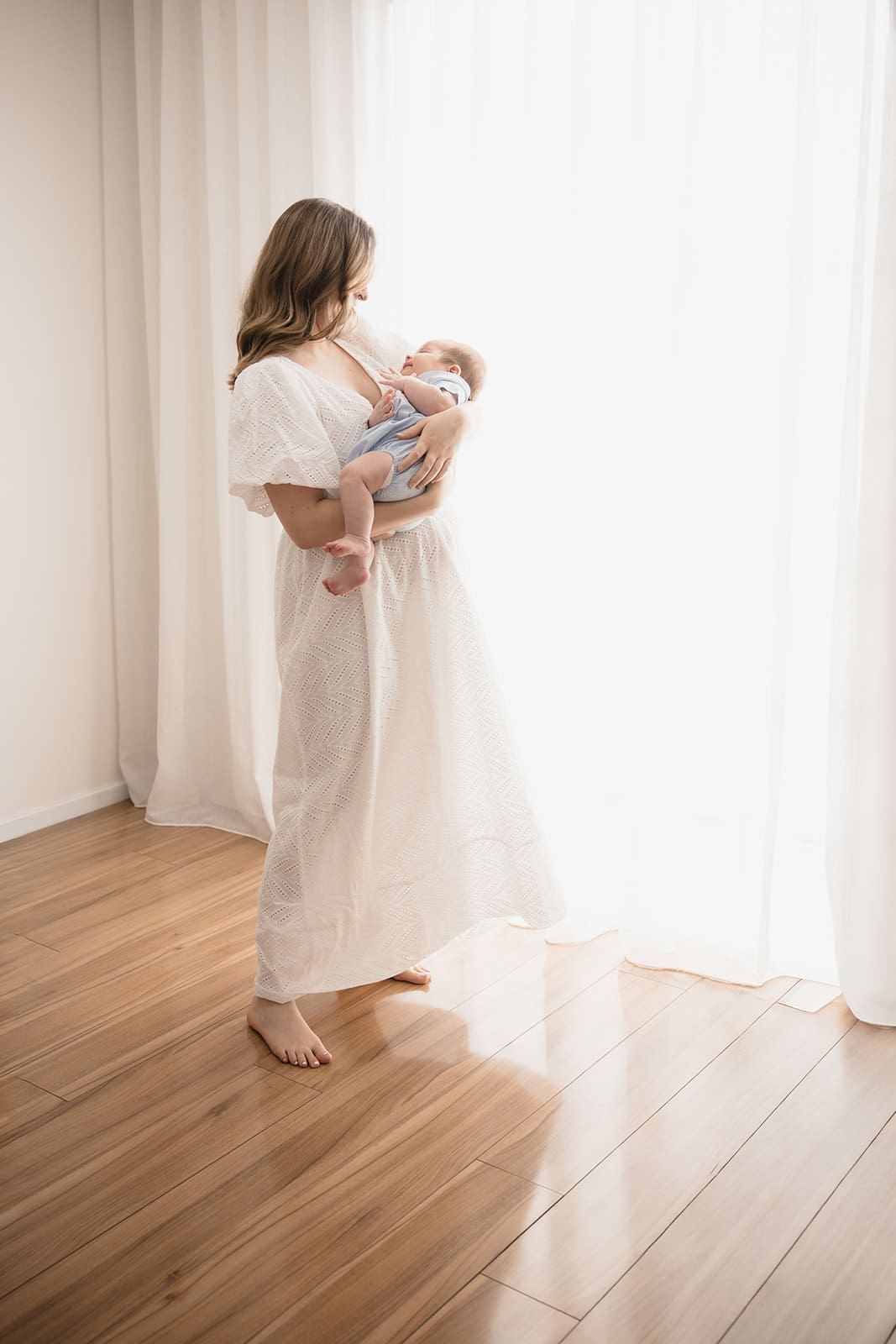 mother holding baby in neutral linen dress during a melbourne newborn photography session