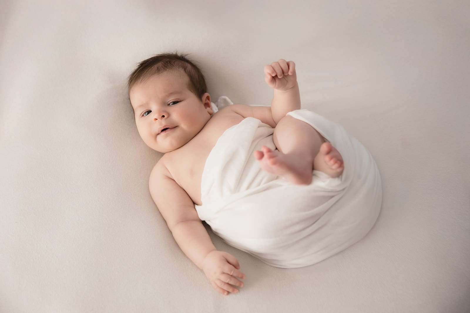 Awake newborn baby wrapped in soft fabric during a studio newborn photography session